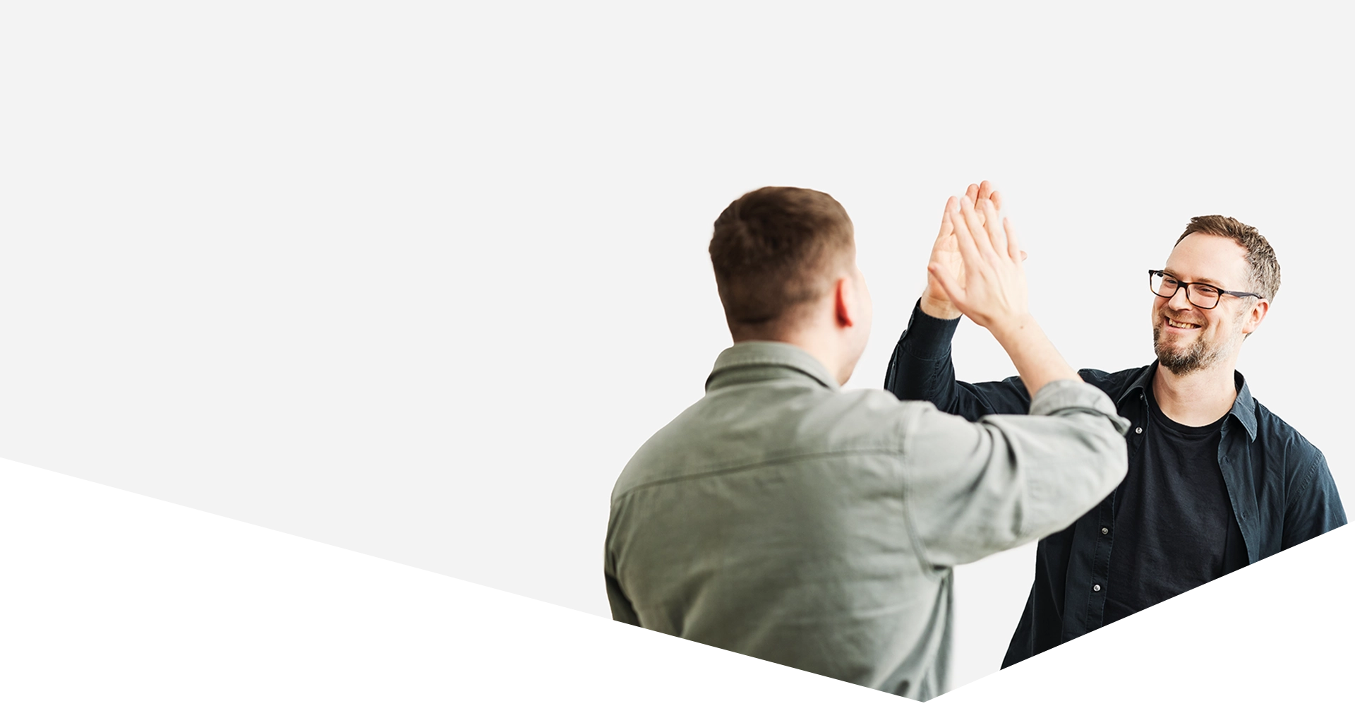 Zwei Kollegen feiern eine erfolgreiche Zusammenarbeit und geben sich motiviert ein High Five in einem Coworking Space in München.