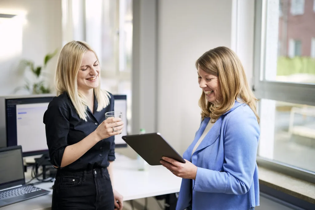 Zwei Personen arbeiten gemeinsam an einem Tablet und besprechen eine digitale Lösung für ein Unternehmen in München.