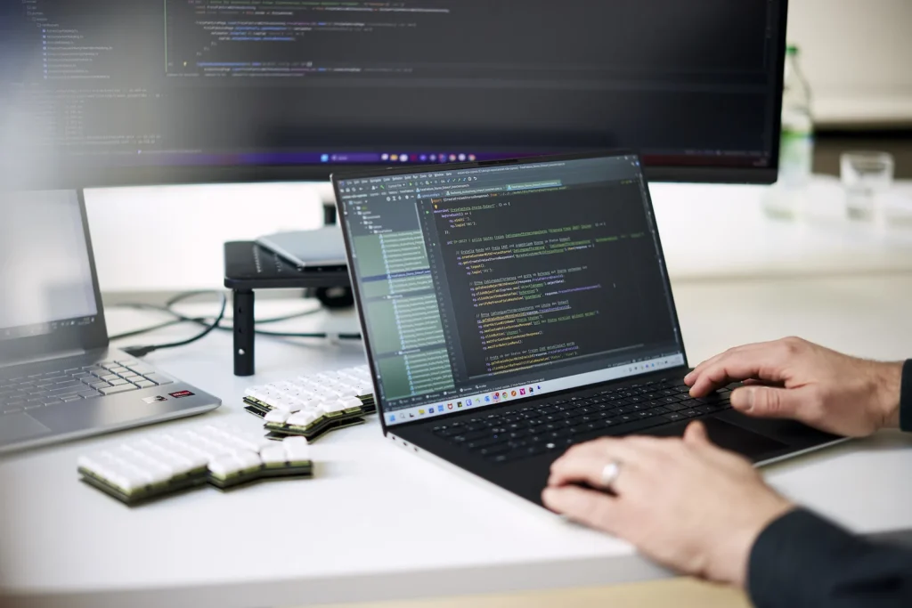 Entwickler arbeitet am Laptop mit offenem Quellcode in moderner Büroumgebung